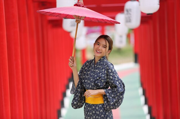 una donna in kimono con in mano un ombrello che entra nel santuario, nel giardino giapponese.