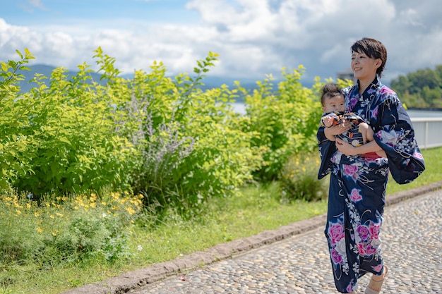 Una donna in kimono tiene in braccio un bambino.