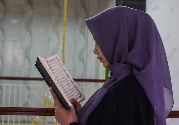Una donna in piedi con un Corano