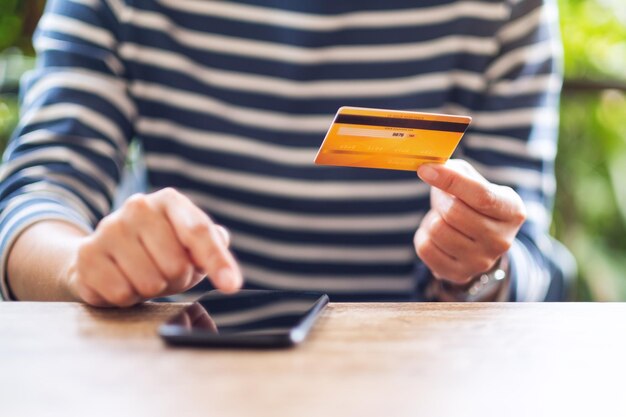 Una donna in possesso di carta di credito e indicando il telefono cellulare per l'acquisto e lo shopping online