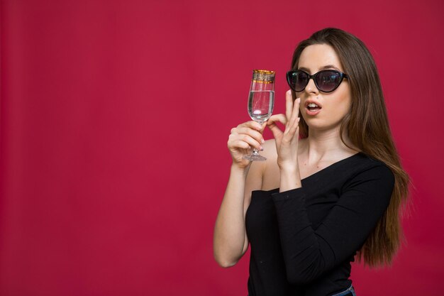 Una donna in studio con un bicchiere di champagne in attesa del Natale Capodanno 2023