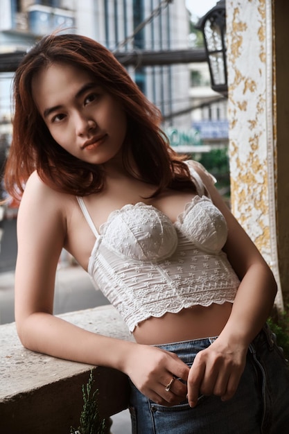 Una donna in top bianco e jeans si siede su un muro a bangkok.