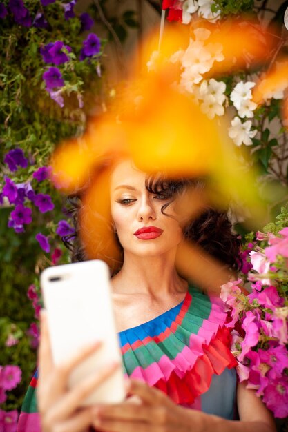 Una donna in un giardino fiorito sta guardando un telefono