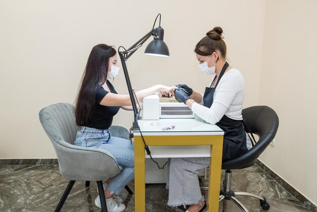 Una donna in un salone di bellezza riceve una manicure in un salone di bellezza da un'estetista che usa una lima per unghie Concetto di cura delle unghie Modellazione delle unghie Lima le unghie con una lima per unghie