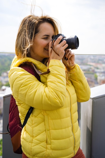 una donna in viaggio scatta foto della città dall'alto. Femmina con una macchina fotografica. Fotografa donne