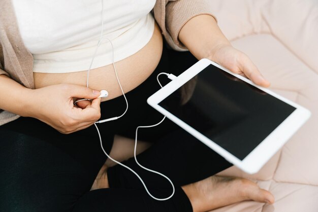 Una donna incinta che ascolta la musica con un tablet