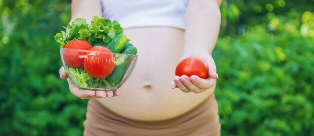 Una donna incinta con le verdure nelle sue mani. Messa a fuoco selettiva. cibo.