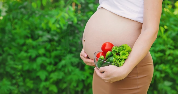 Una donna incinta con le verdure nelle sue mani. Messa a fuoco selettiva. cibo.