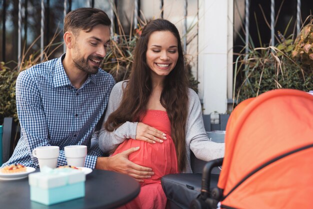 Una donna incinta con un uomo è seduta al tavolo di un caffè.