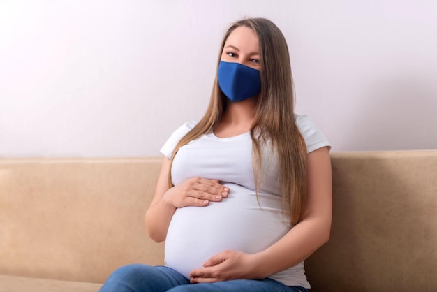 Una donna incinta con una maschera blu si siede sul divano