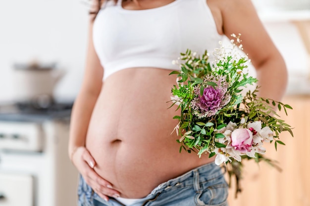 Una donna incinta detiene bellissimi fiori Carino concetto sano gravidanzaFesta della mamma