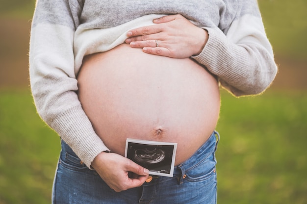 Una donna incinta è in possesso di una foto del suo bambino Ultrasuoni, all'aperto.