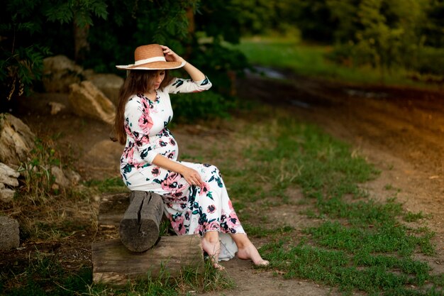 Una donna incinta in un vestito cammina nella natura nella foresta in estate