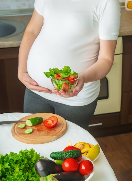 Una donna incinta mangia frutta e verdura