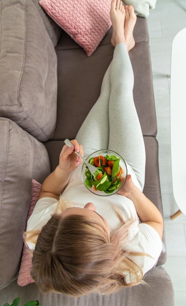 Una donna incinta mangia un'insalata con verdure Fuoco selettivo