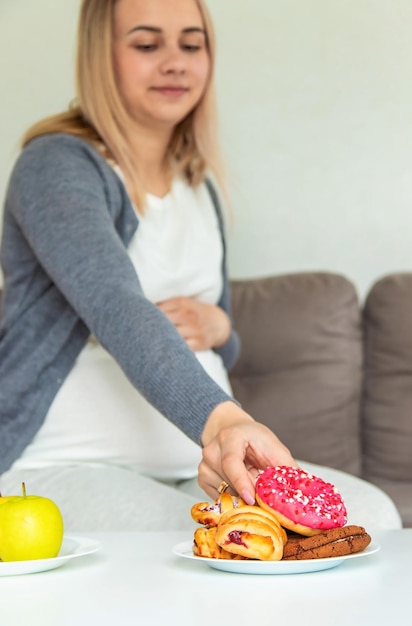 Una donna incinta mangia una ciambella dolce Fuoco selettivo