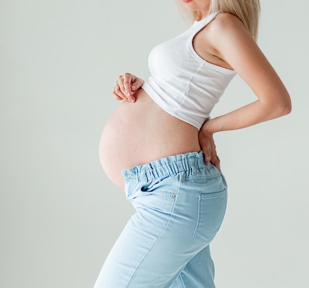 Una donna incinta tiene la parte bassa della schiena e lo stomaco Aspettando un bambino e la maternità Festa della mamma
