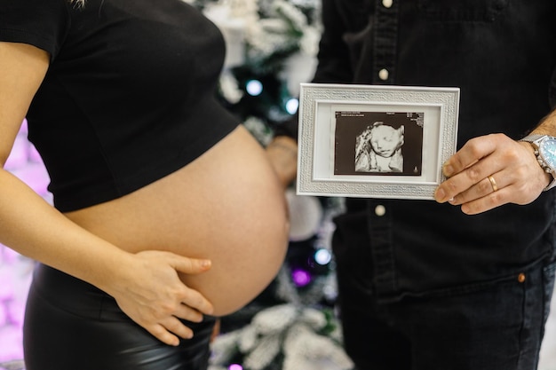 Una donna incinta tiene una foto della sua pancia incinta.