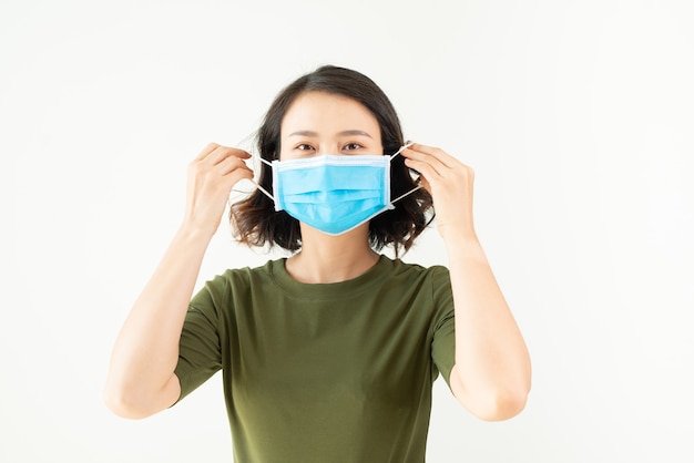 Una donna indossa una maschera per proteggersi da virus, bellezza asiatica, muro bianco