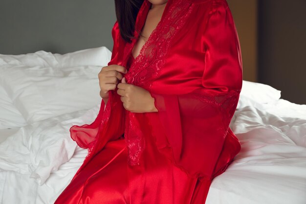 Una donna indossava una camicia da notte rossa sexy e un accappatoio di satin a maniche lunghe.