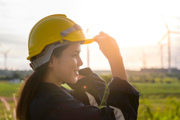 Una donna ingegnere si sta mettendo un casco protettivo in testa al tramonto