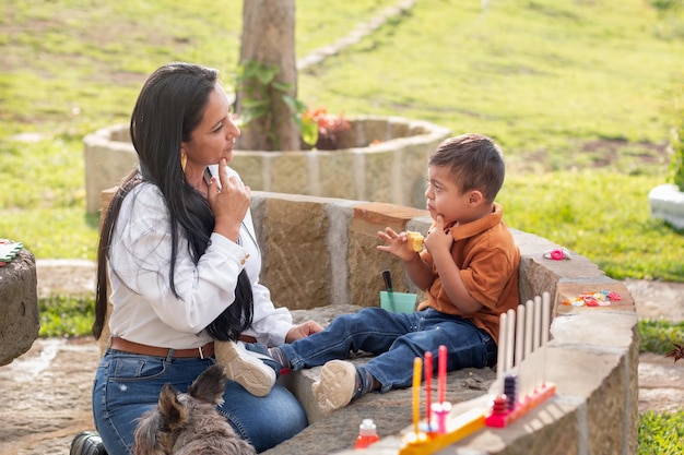 Una donna insegna a suo figlio con sindrome di Down a masticare il cibo in una bella giornata di sole in un parco naturale