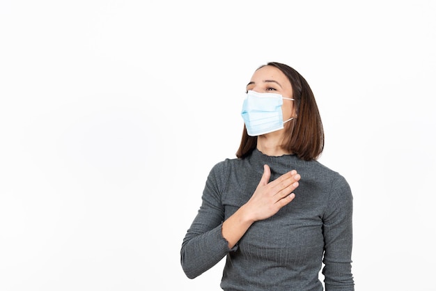 Una donna ispanica saluta con la mano sul petto mentre indossa una maschera medica