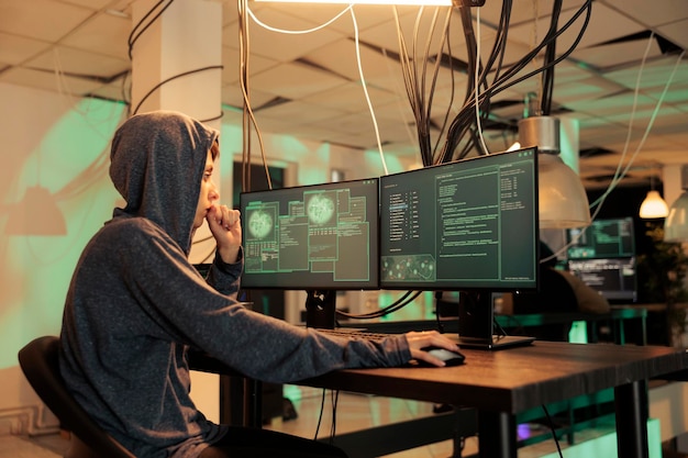 Una donna ladra che cerca di hackerare il sistema informatico di notte, utilizzando il codice per entrare nel server di sicurezza. Hacker donna che svolge attività criminali e ruba password per richiedere ransomware.