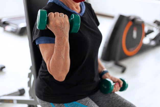 Una donna latina anziana si allena con i manubri in palestra