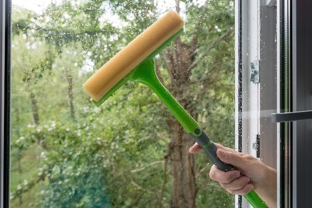una donna lava una finestra con una lavabicchieri dopo una forte pioggia