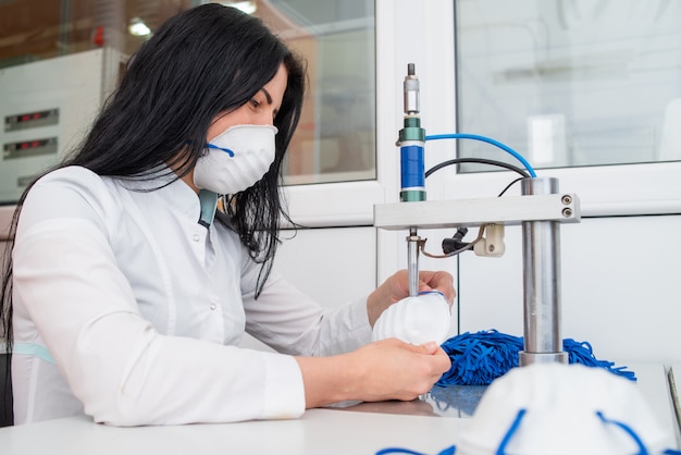 Una donna lavora in una macchina per la produzione di maschere mediche con nanofibre e anelli di saldatura con ultrasuoni.