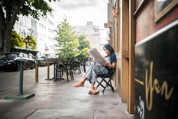 una donna legge un giornale fuori da un caffè