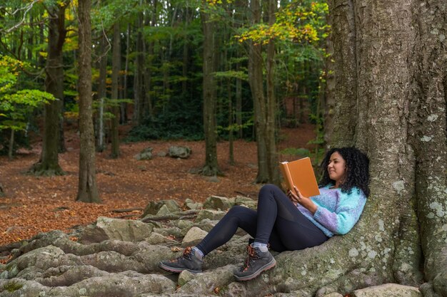 Una donna legge un libro nella foresta.