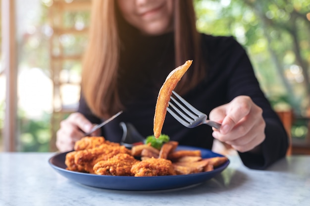 Una donna mangia patatine fritte e pollo fritto in un ristorante