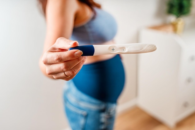 Una donna mantiene un test di gravidanza positivo Concentrati sul test