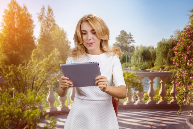 Una donna matura e affascinante guarda qualcosa sul tablet.