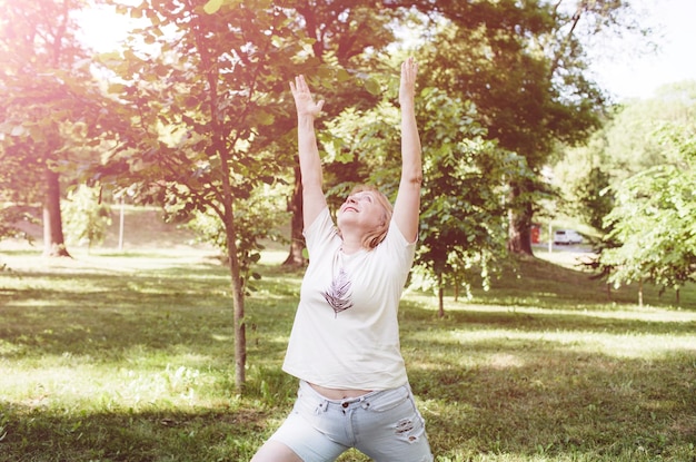 Una donna matura in una maglietta fa esercizi di fitness e fa yoga all'aperto uno stile di vita sano