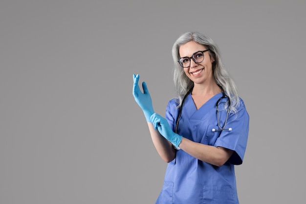 Una donna medico allegra che indossa guanti medici su uno sfondo grigio