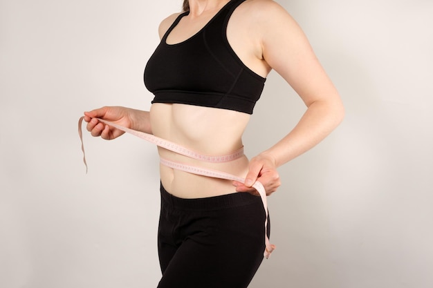 Una donna misura la circonferenza dell'addome con un nastro di centimetro