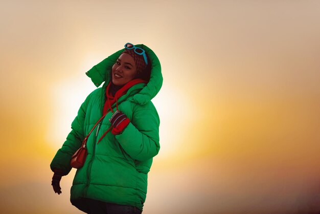 Una donna moderna in hijab con una giacca verde in posa all'aperto.