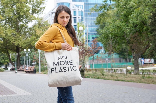 Una donna mostra una borsa riutilizzabile in tessuto con la scritta Niente più plastica.