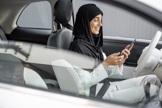 Una donna musulmana parla al telefono mentre guida un'auto