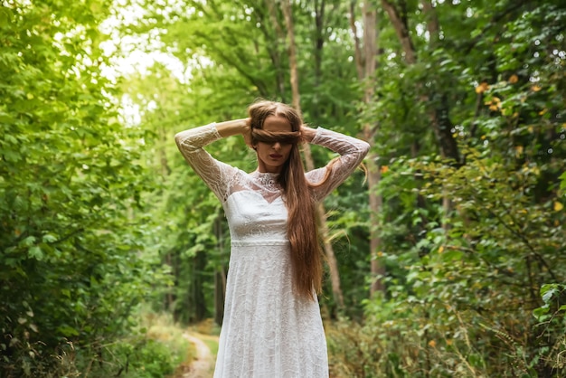 Una donna nella foresta che si copre gli occhi con i capelli