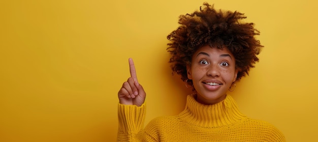 Una donna nera sorridente dai capelli ricci indica il dito su uno sfondo giallo