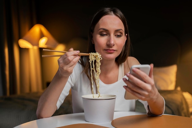 Una donna occupata usa uno smartphone mentre cena in camera da letto uno studente mangia fast food mentre lavora