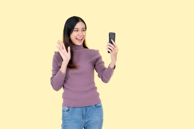 Una donna positiva si diverte a parlare durante una videochiamata mentre si trova su uno sfondo giallo isolato