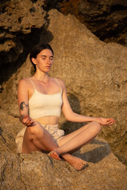 Una donna pratica yoga sugli scogli