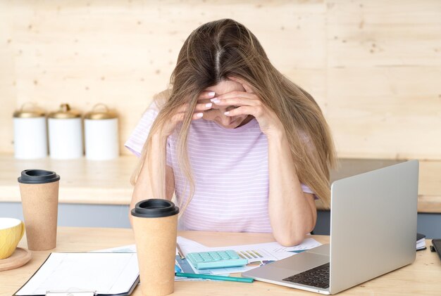 Una donna premurosa che beve molto caffè mentre fa un lavoro creativo