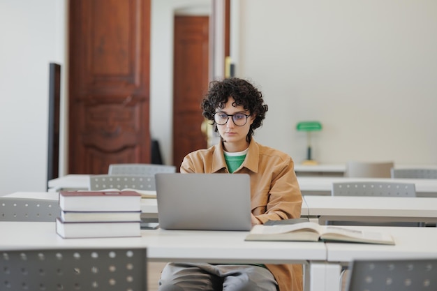 Una donna premurosa in biblioteca guarda il webinar di formazione online e prende appunti sul taccuino