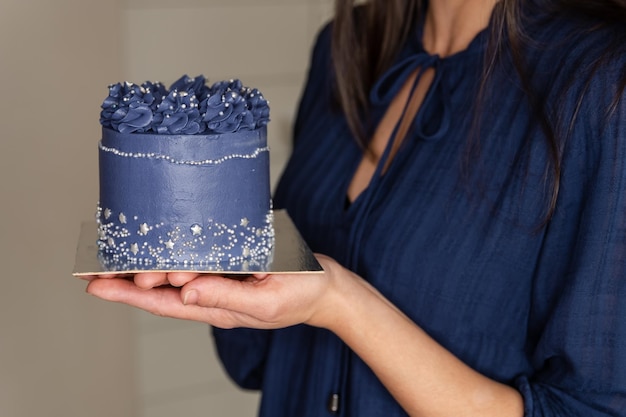 Una donna prepara una torta con crema blu Pasticcere detiene una torta